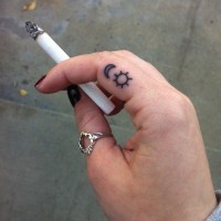 Small black ink sun and moon tattoo on finger