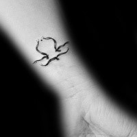 Small black ink wrist tattoo of mystic symbol