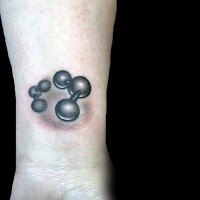 Small black ink wrist tattoo of small atoms