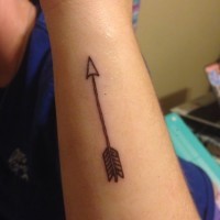 Small gray-ink arrow tattoo on forearm