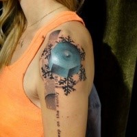 Small illustrative style colored shoulder tattoo of blue figure with snowflake and lettering