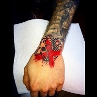 Small photoshop style colored wrist tattoo of atom with red cross