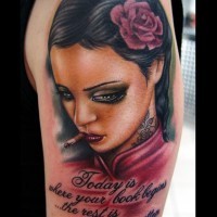 Tatuaje en el brazo, mujer con flor delicada en el pelo que fuma y inscripción