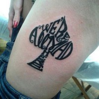 Tatuaje en el muslo,  símbolo pica formado de letras, tinta negra