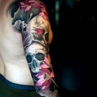 Spectacular combined colored beautiful flowers tattoo on sleeve with human skulls