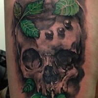 Spectacular realism style colored thigh tattoo of human skull with leaves