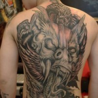 Tatuaje en la espalda, cara de monstruo con colmillos y lengua larga
