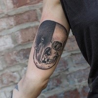 Stippling style black ink biceps tattoo of half human half birds skull