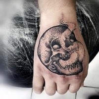 Stippling style black ink hand tattoo of small skull and fog