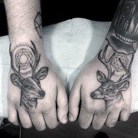 Stippling style black ink hands tattoo of mystical deers with various ornaments