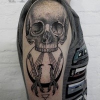 Stippling style black ink shoulder tattoo of human skull and eagle legs