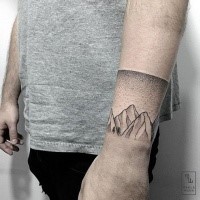 Stippling style wrist tattoo of mountains