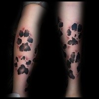 Strange looking black ink leg tattoo of animal paw prints