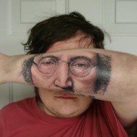 Strange looking colored Lennon face tattoo on arm