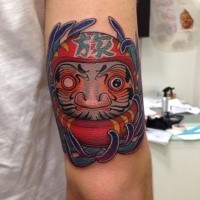 Stunning colored arm tattoo of daruma doll with lettering and flowers