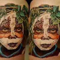 Atemberaubendes mehrfarbiges Oberschenkel Tattoo von Tribal Kind Porträt mit Blumen
