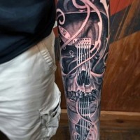 Tatuaje en el antebrazo, cráneo humano con guitarra, diseño bien dibujado