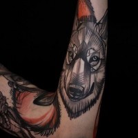 Stylized colored wolf's head forearm tattoo in original technique