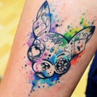 Stylized little dog's portrait with unusual eyes tattoo on forearm in watercolor style