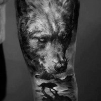 Super realistic dark wolf with silhouette of a wolf forearm tattoo