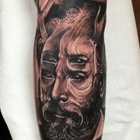 Surrealism style black ink arm tattoo of man with deer horn and four eyes
