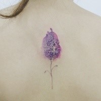 Sweet looking colored back tattoo of little flower