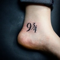 Symbolische Zahlen 9 3/4 Tattoo am Knöchel in dunkler schwarzer Tinte