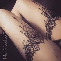 Symmetrical colored illustrative thigh tattoo of floral ornaments by Caro Voodoo