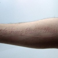 Tatuaje en tinta blanca la inscripción a lo largo del brazo