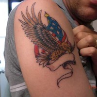 el tatuaje patrioto de una aguila con la bandera americana hecho en color en el hombro