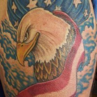 el tatuaje patriota conn una aguila  sobre la bandera americana hecho en color en el hombro