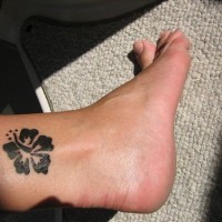 Tattoo von schwarzer runder Blume in der Knöchelgegend