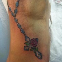 Tattoo von blauer Kette mit Kreuz und Blume in der Knöchelgegend