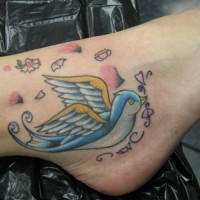 Flying blue and yellow bird ankle tattoo