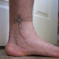 Nichtfarbiges Tattoo vom Kreuz in der Knöchelgegend