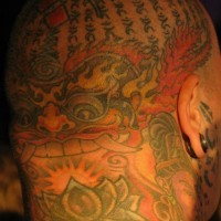 Tatuaje en la cabeza, monstruo con colmillos largos, montón de jeroglíficos