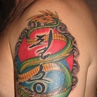 Tatuaje coloreado del clásico dragón verde con escritura.
