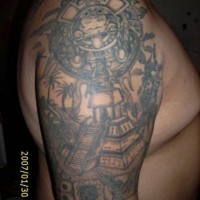 Tatuaje en el hombro del sol en piedra y una pirámide azteca.