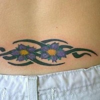 Le tatouage d'entrelacs tribal avec des fleurs en couleur sur le bas du dos