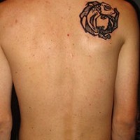 Tatuaje en el hombro de un pequeño pez negro.