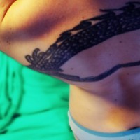 Schwarzes Tattoo mit geflochtenem Band am oberen Rücken