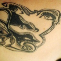 Schwarzes Gesicht einer Frau auf Tattoo am oberen Rücken