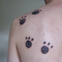 Tracks on upper back black animal's tattoo