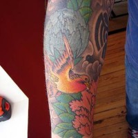 Tatuaje en el brazo, diseño de ave entre flores