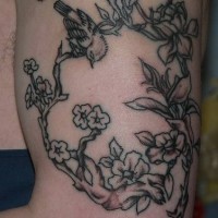 Tatuaje en el brazo, rama con ave pequeña