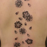 El tatuaje de una flor de loto y muchas flores de cereza de color negro en la espalda