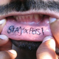Bottom lip tattoo, stay x posl, black styled inscription