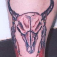 Le tatouage de la crâne de taureau avec des plumes sur les cornes
