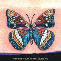 Le tatouage de papillon super multicolore sur le bas du dos