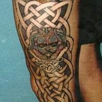 Tatuaje, en toda la pierna, en estilo celta con un ojo de bestia y un gnomo
